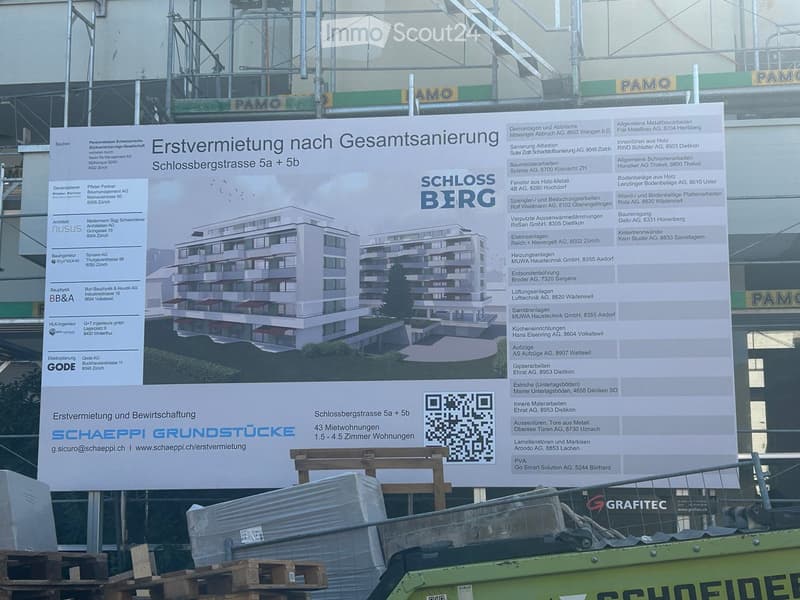 A large advertisement board displaying details about a property renovation and rental project, including a rendered image of the building and contact information.