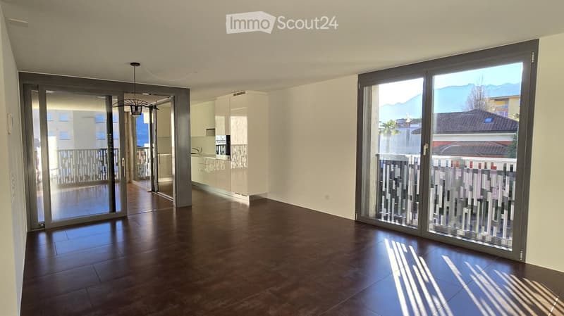 Open-plan living room, with wooden floors, kitchen area, sliding doors, balcony