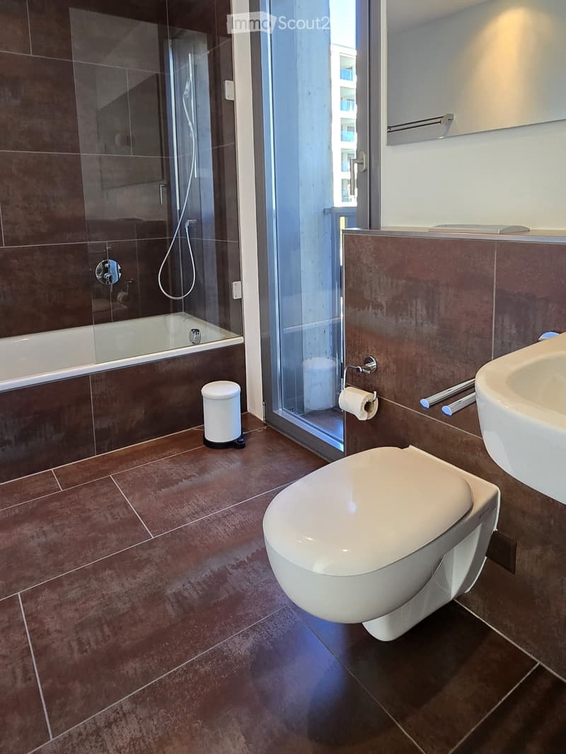 modern bathroom with brown tiles, bathtub, toilet, sink, mirror, glass door, showerhead