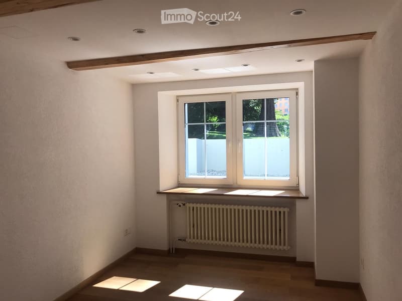 Empty room with wooden flooring, white walls, a window with a radiator below, and recessed ceiling lights.