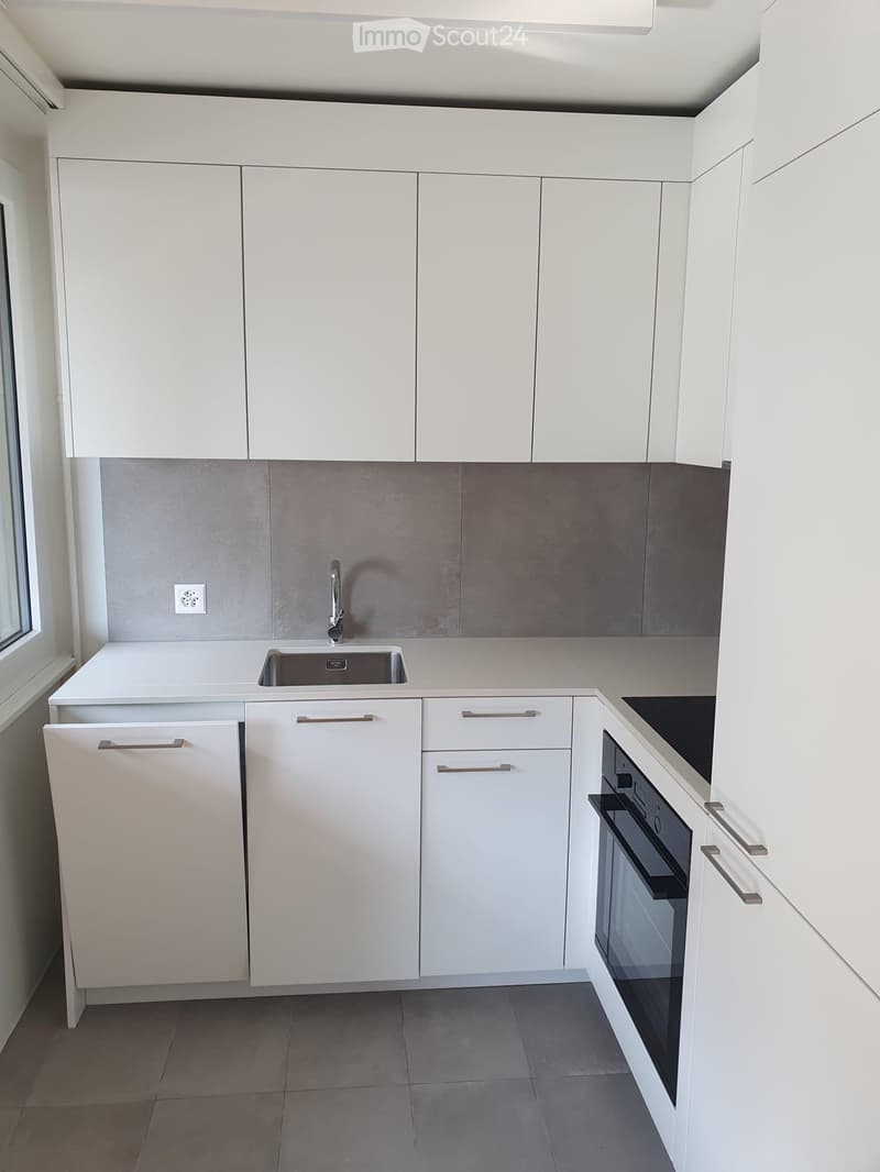 Modern kitchen with white cabinets, stainless steel sink, faucet, oven, and dishwasher.