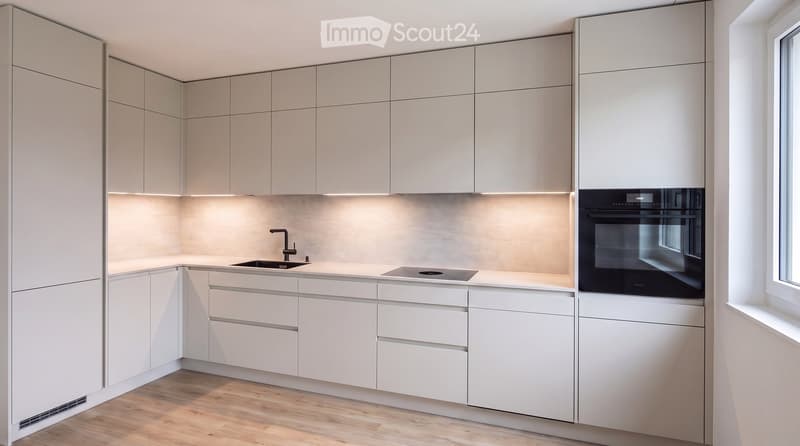 Modern kitchen with light grey cabinets, white countertops, a built-in oven, and a sink with a faucet.