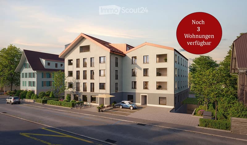 Modern multi-story residential building with balconies, surrounded by greenery and parking area.