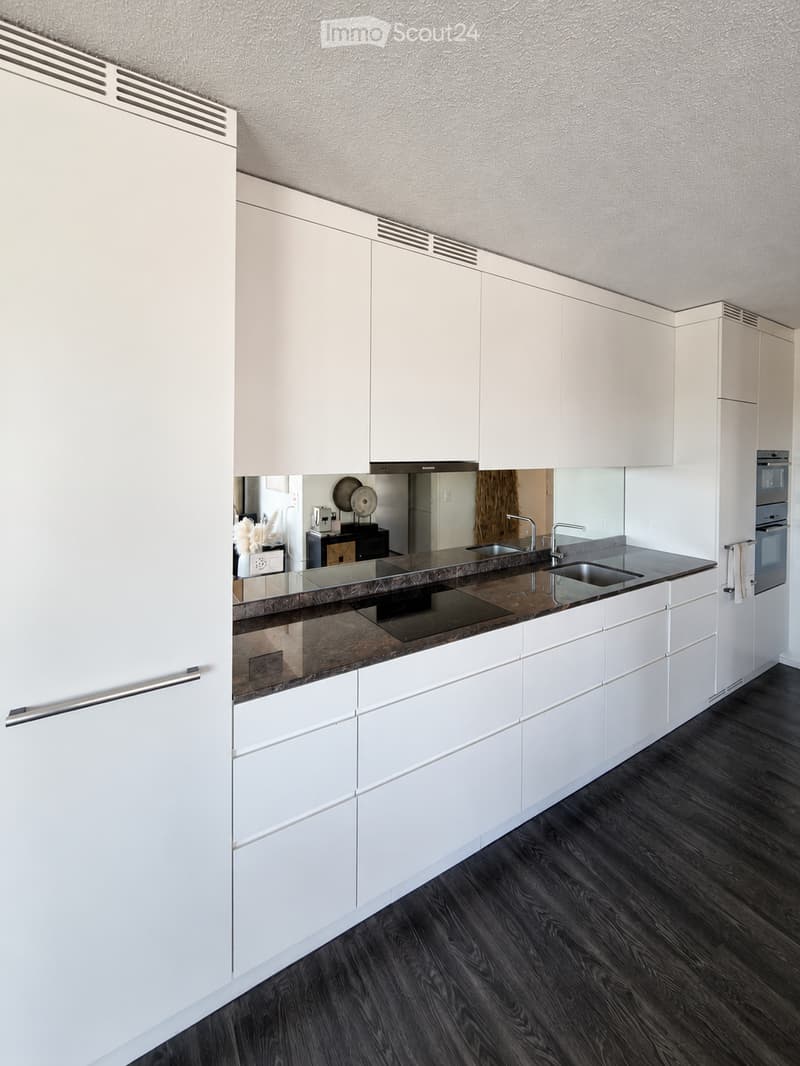 Modern kitchen with white cabinets, dark countertops, and stainless steel appliances.