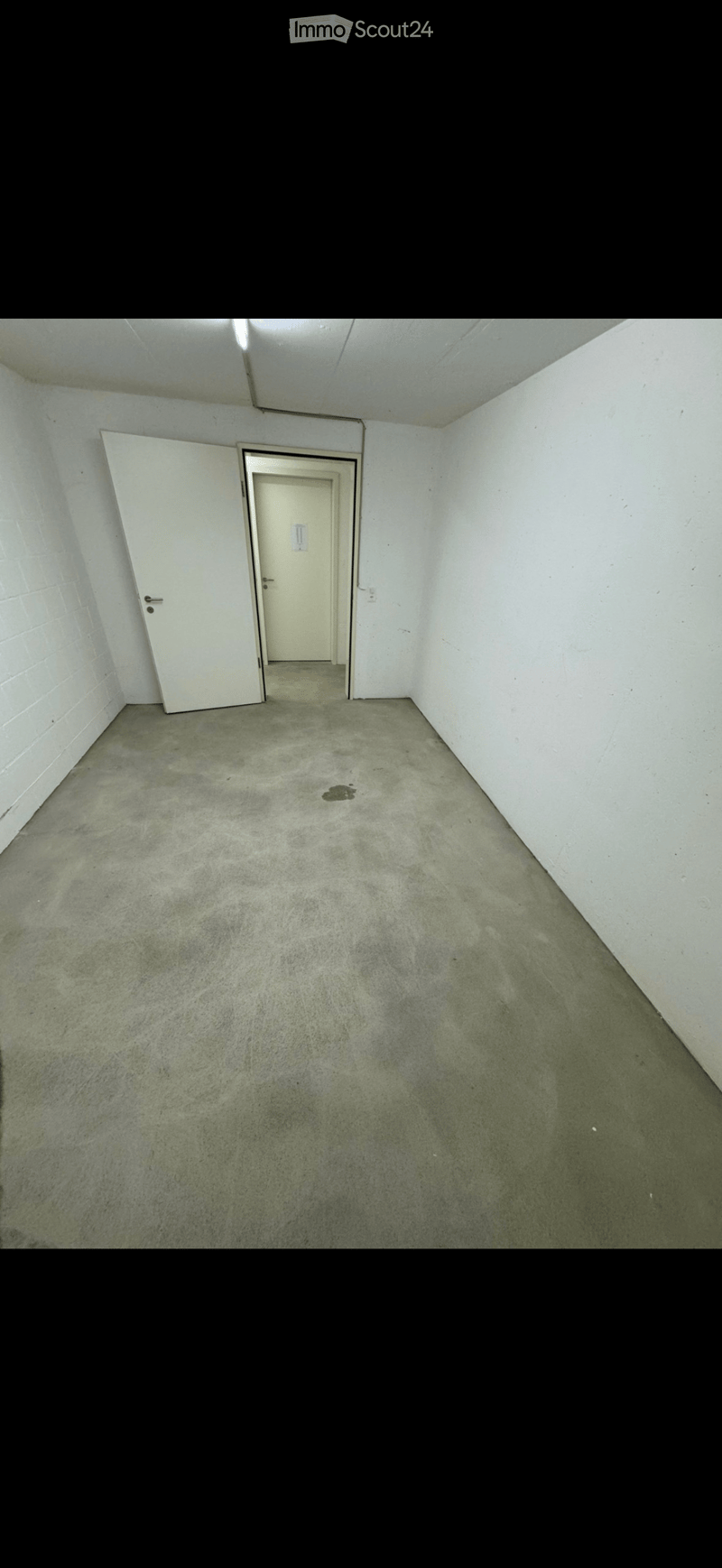 Empty room with concrete floor, white walls, and two doors.