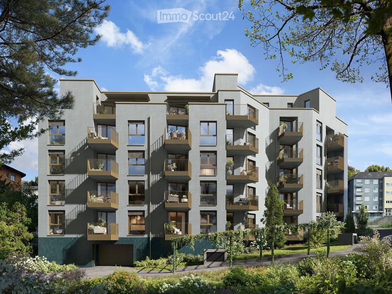 Modern multi-story apartment building with balconies, large windows, and a garage entrance.