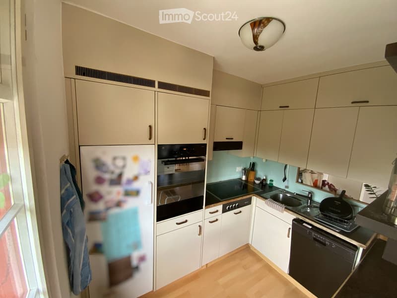 Modern kitchen with light-colored cabinets, stainless steel appliances, and a light blue backsplash. Features include a refrigerator, oven, dishwasher, sink, and countertop items.