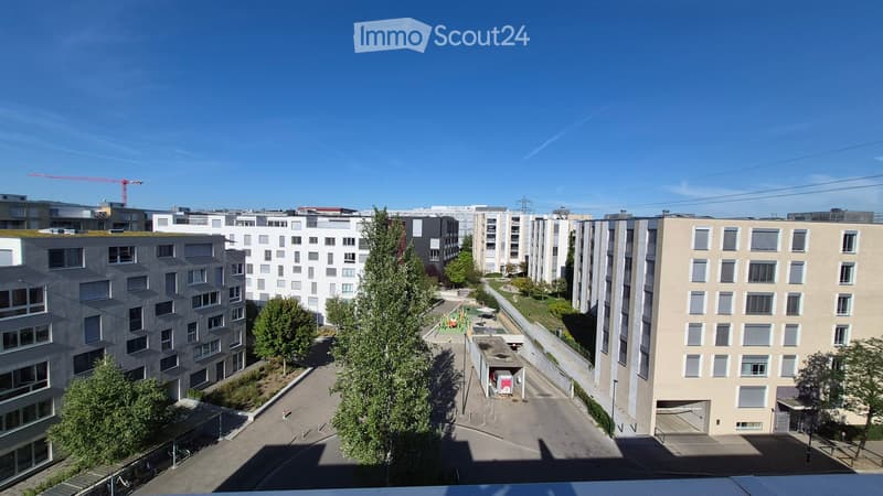 View of a modern residential complex with multiple apartment buildings, green spaces, and a playground area.