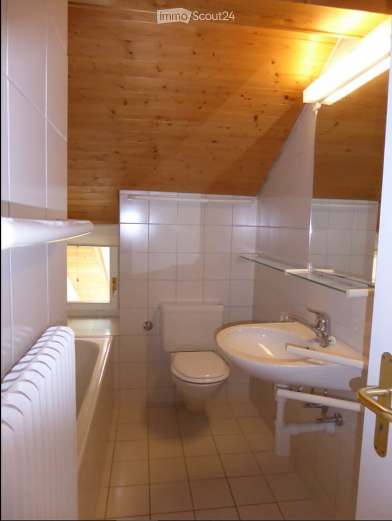 Bathroom with wooden ceiling, white tiled walls, sink, toilet, bathtub, and a glass shelf above the sink.