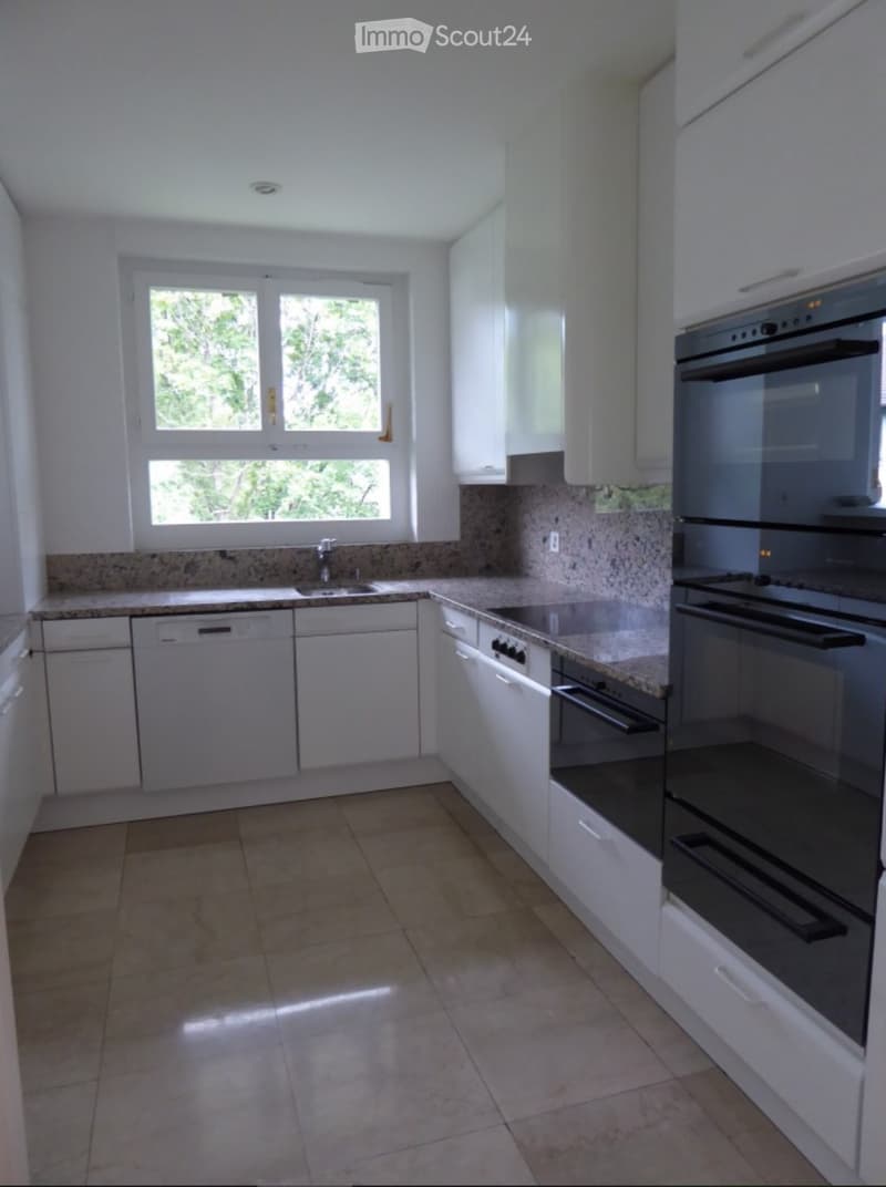 Modern kitchen with white cabinets, granite countertops, and stainless steel appliances including an oven and dishwasher.