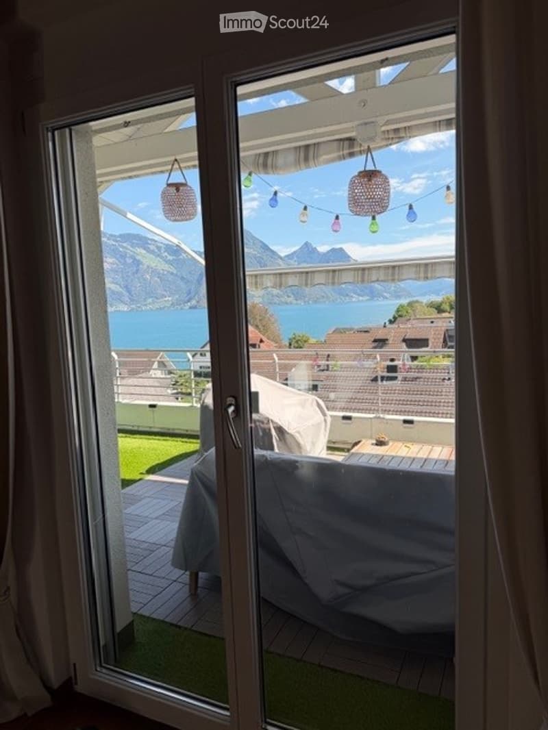 Balcony with wooden decking, covered seating area, and scenic mountain and lake view.