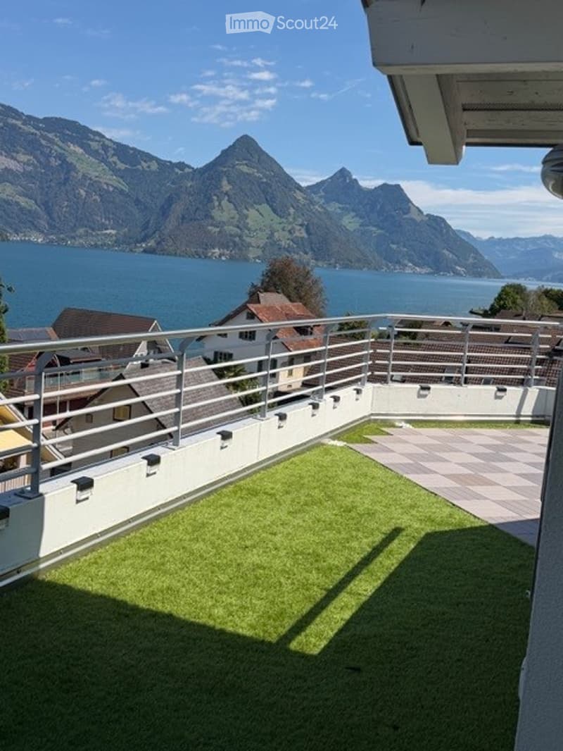 Balcony with artificial grass, metal railing, and scenic mountain and lake view.