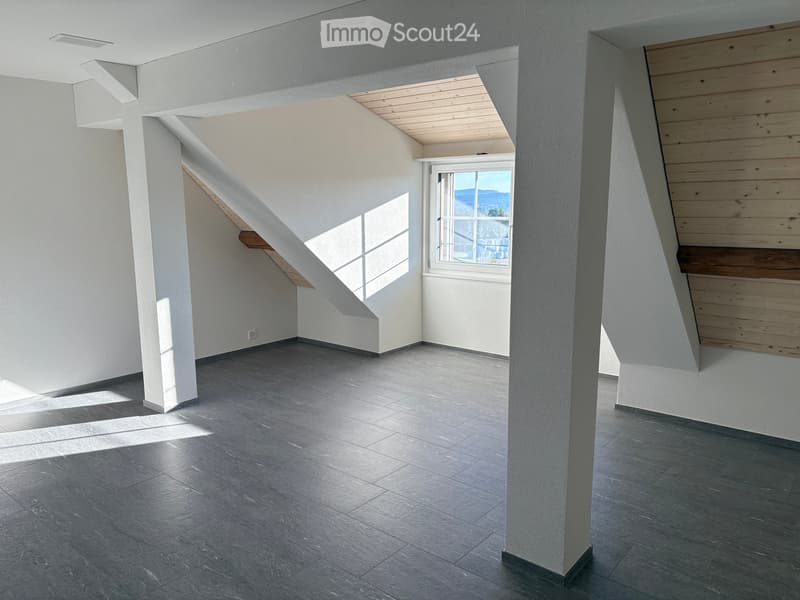 Empty room with grey tiled floor, white walls, and a large window with a view of the landscape.
