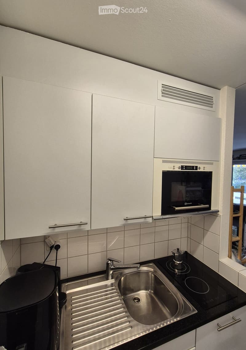 Modern kitchen with white cabinets, stainless steel sink, electric stovetop, and built-in oven.