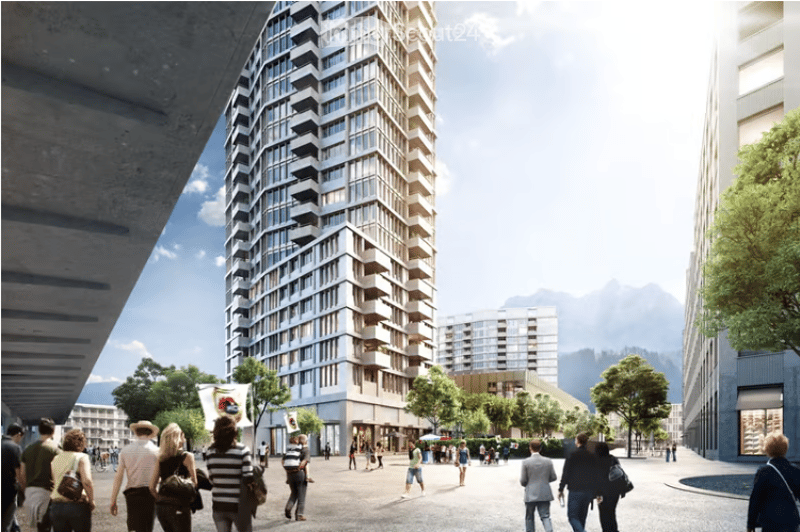 A modern urban setting with a tall, contemporary building featuring numerous balconies and large windows. The surrounding area includes pedestrians, trees, and smaller structures, with a scenic mountain backdrop.