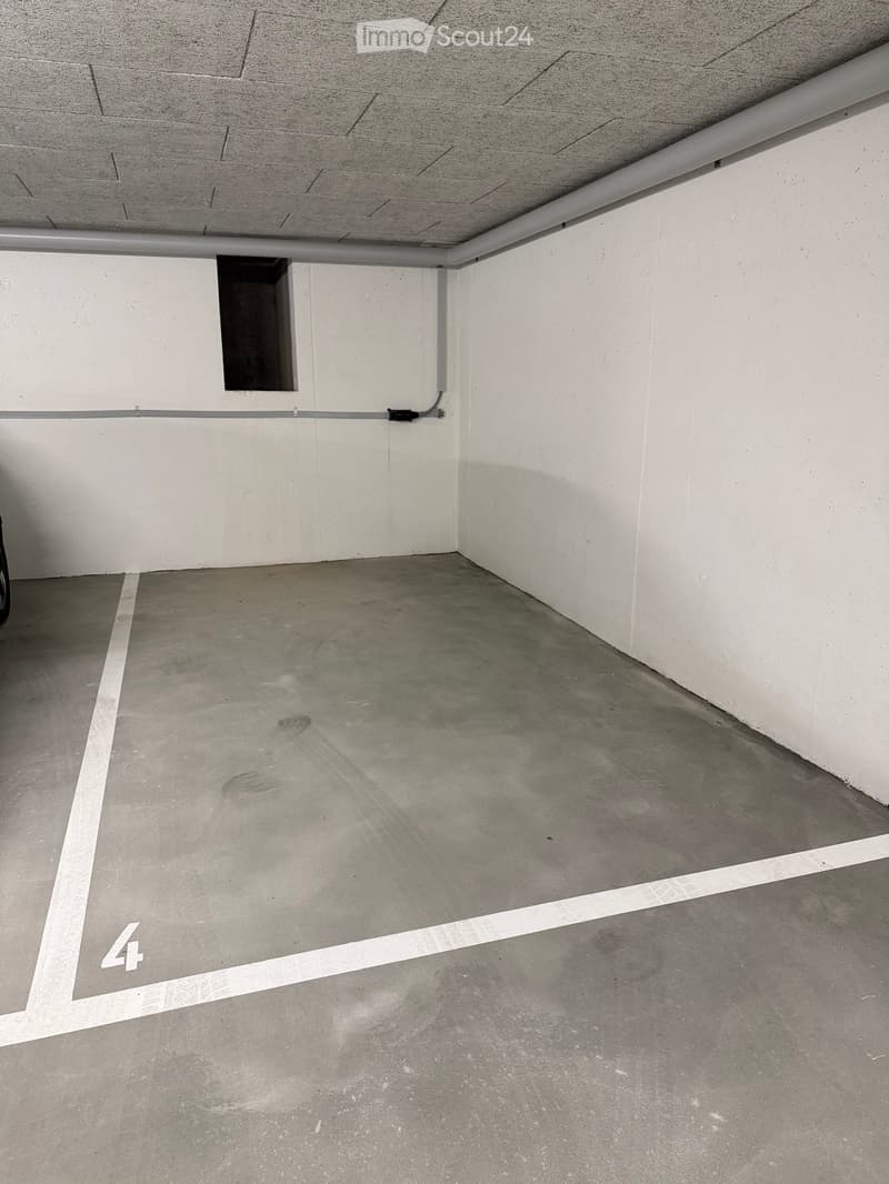 Empty underground parking space with concrete floor and white walls, marked with number '4'.