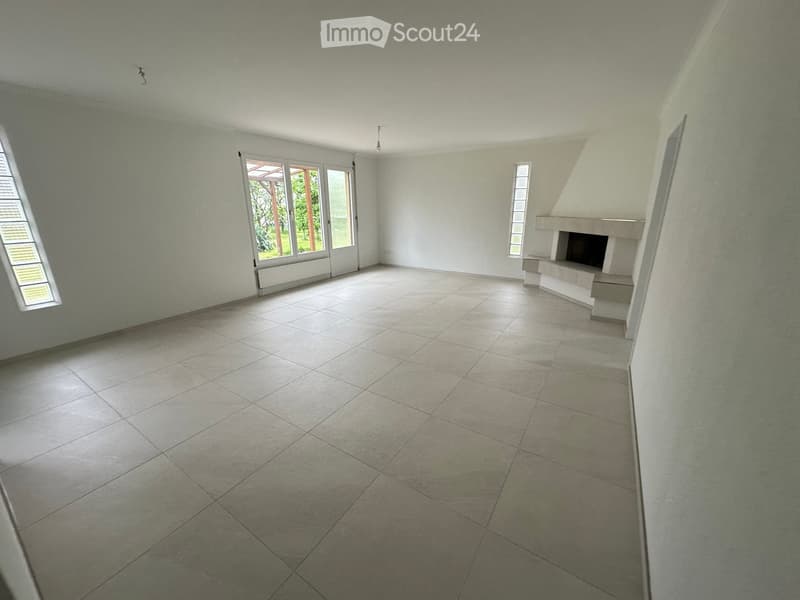 Empty room with tiled floor, white walls, large windows, and a fireplace.
