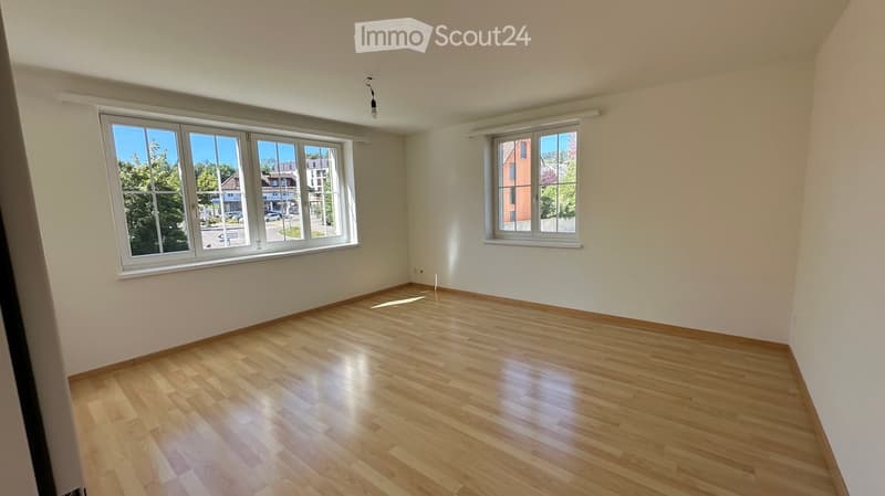 Empty room with wooden flooring and large windows, no furniture or equipment present.