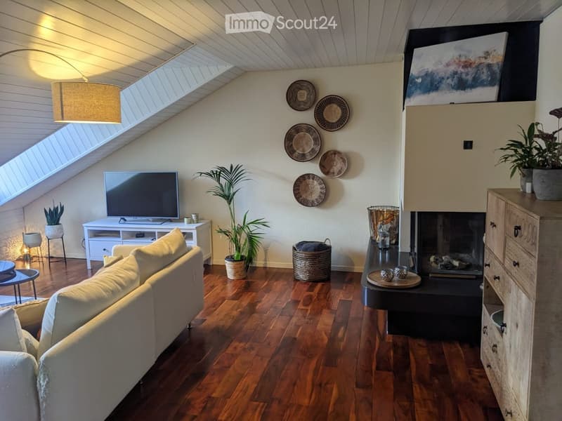 Living room with wooden flooring, a fireplace, a sofa, coffee table, television, and decorative plants.