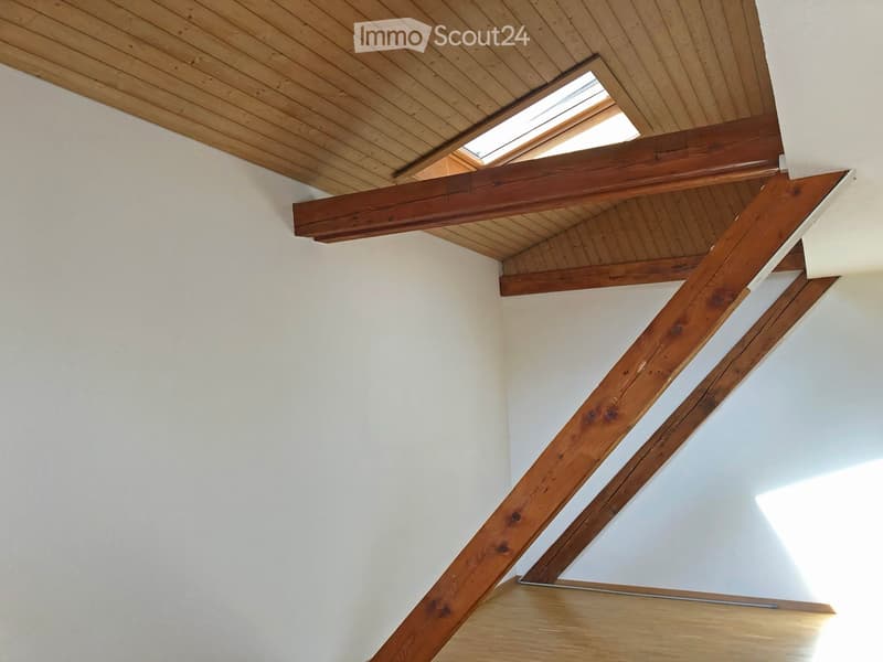 Bright hallway with wooden beams and exposed wooden ceiling, white walls, and a skylight window allowing natural light to enter.