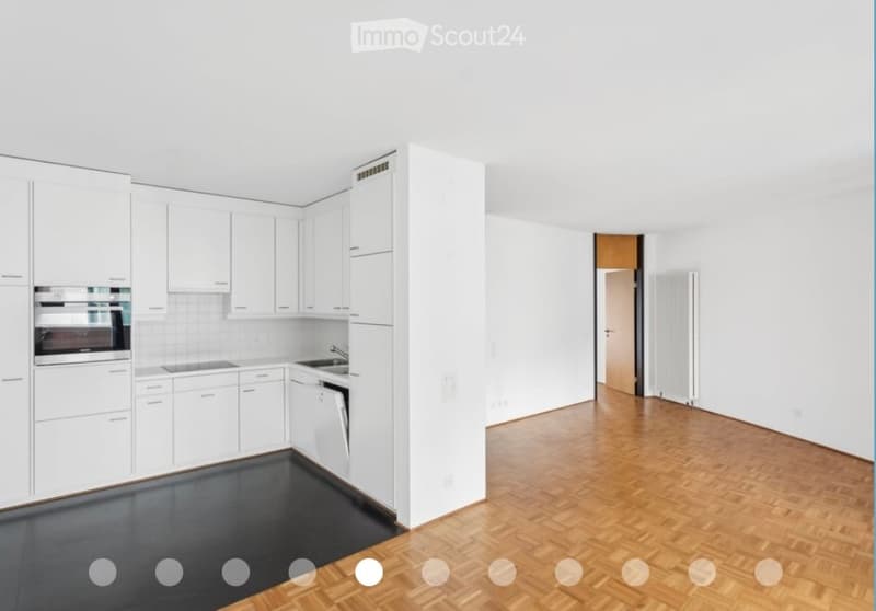Modern kitchen with white cabinets, stainless steel appliances, and wooden flooring.