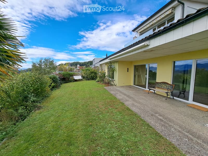 Garden with a well-maintained lawn, gravel pathway, and a bench near the house entrance.