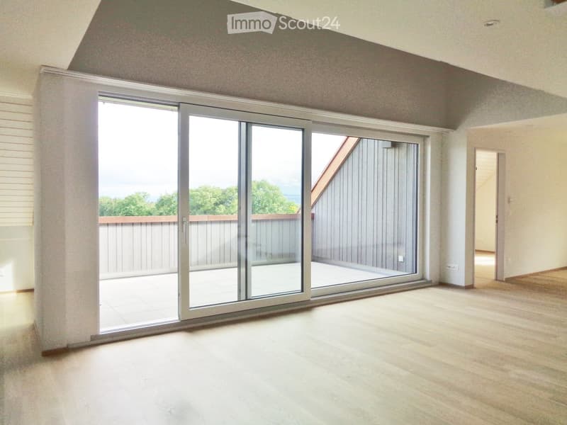 Empty room with wooden flooring, large sliding glass doors leading to a balcony, and white walls.