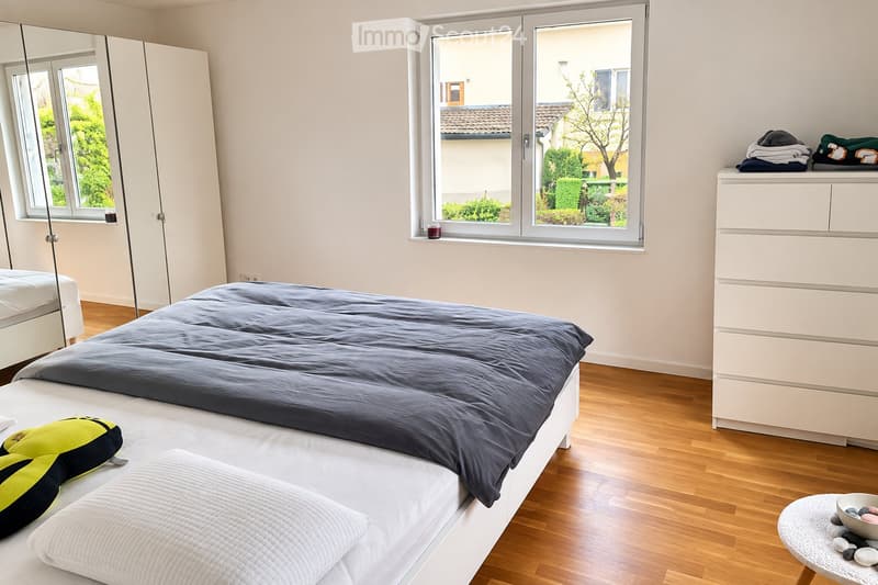 Modern bedroom with two single beds, a large mirror, a wardrobe, and a small table with decorative items.