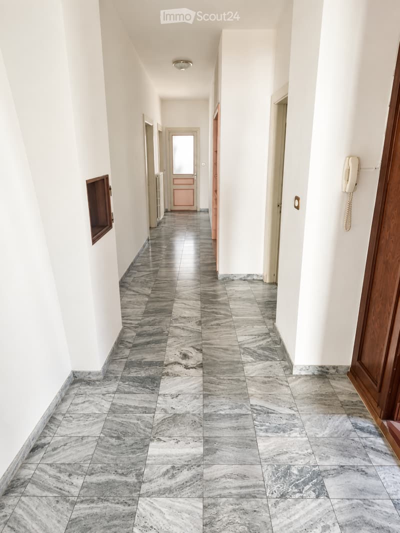 Empty hallway with marble tiled flooring, white walls, and several doors leading to rooms.