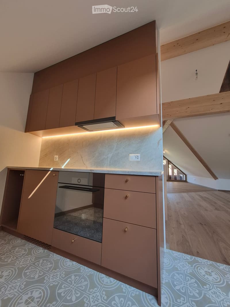 Modern kitchen with built-in oven, sleek cabinets, and a decorative tiled floor.