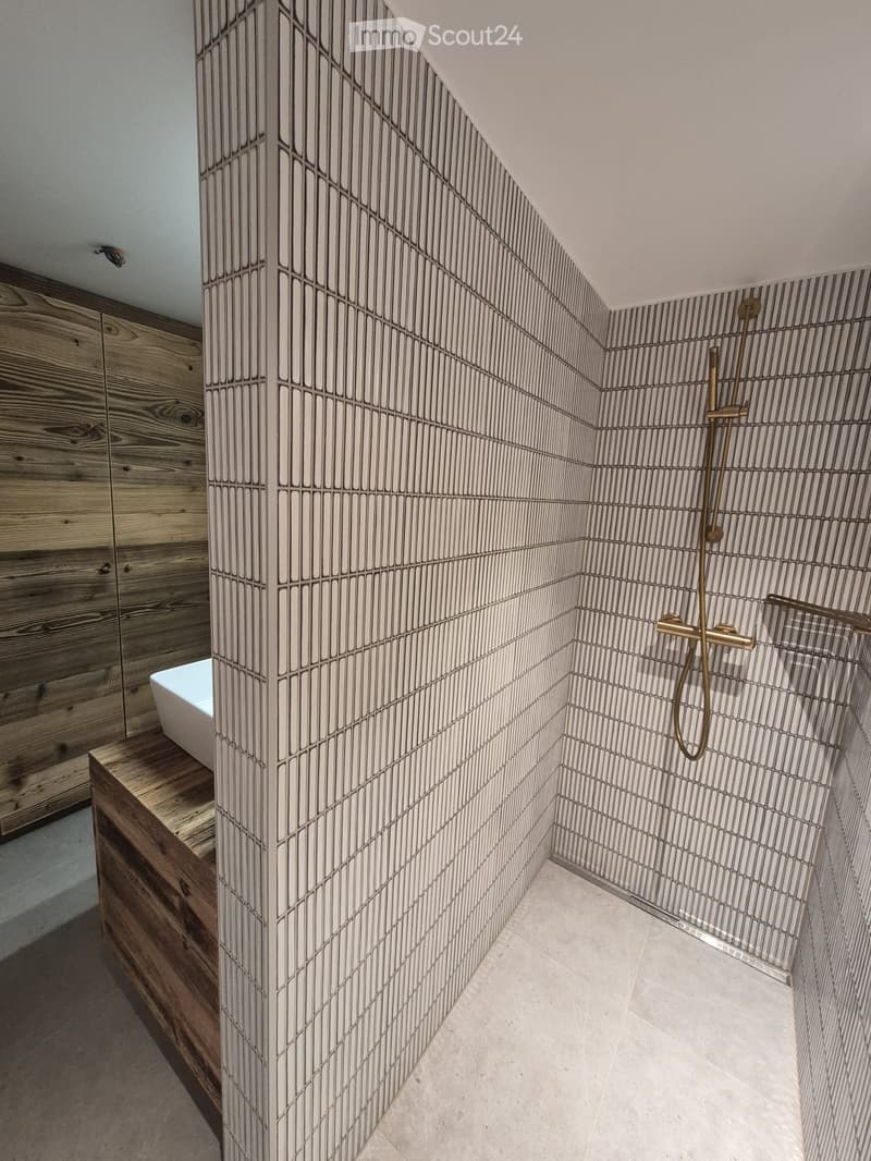 Modern bathroom with wooden cabinetry, a bathtub, and a shower area with a sleek, geometric tile design.