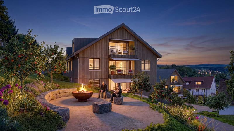Modern two-story house with wooden facade, large windows, and balconies, surrounded by a landscaped garden with a fire pit, seating area, and fruit trees.
