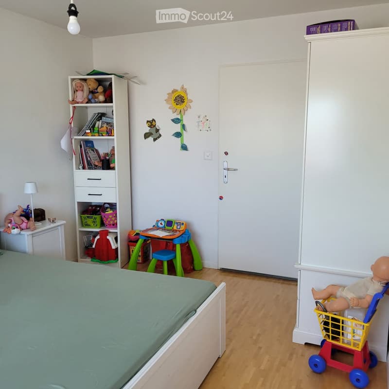 A child's bedroom with a bed, wardrobe, shelf, toy cart, and various toys.