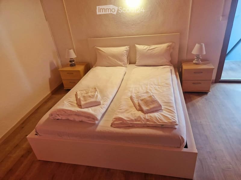 Cozy bedroom with a single bed, two nightstands with lamps, and neatly arranged towels on the bed.