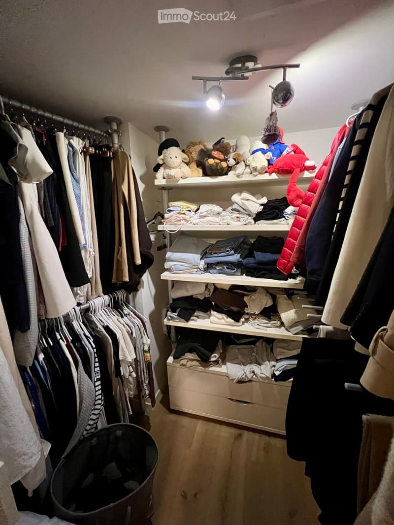Well-organized closet with multiple clothing racks, shelves filled with folded clothes, toys, and a large drawer unit.