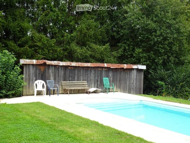 Outdoor area with a swimming pool, wooden shed, and seating including chairs and a bench.