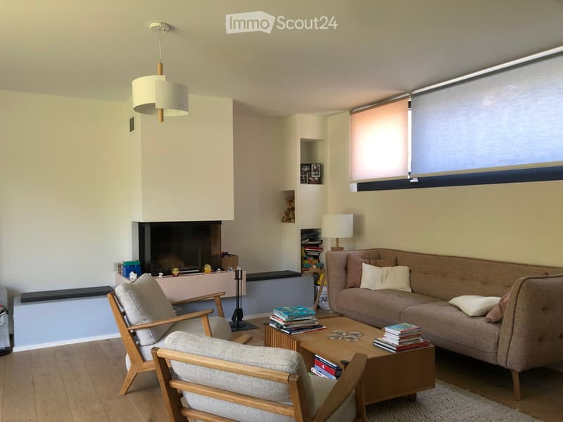 Modern living room with a fireplace, a sofa, a coffee table, a wooden chair, and a table lamp.