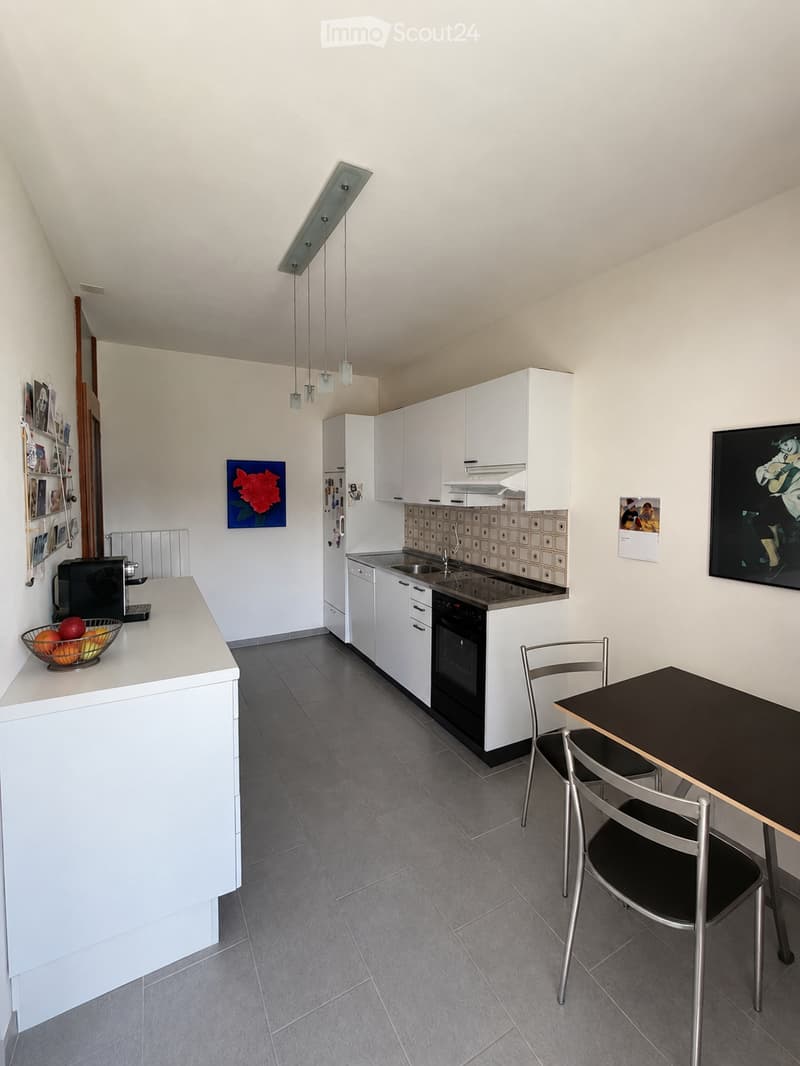 Modern kitchen with white cabinets, stainless steel appliances, a central island, and a dining area with a table and chairs.