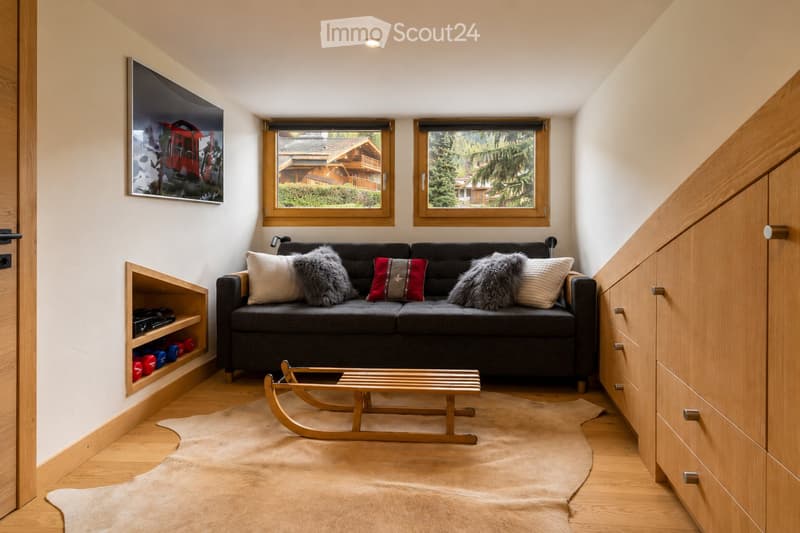 Modern living room with a dark grey sofa, wooden coffee table, fur rug, and a small wooden sleigh as a coffee table.