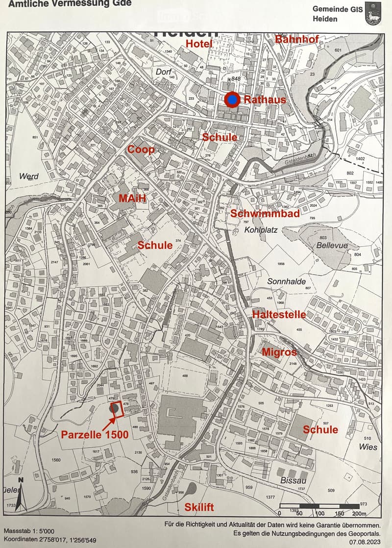 Floor plan of a town with labeled locations including Hotel, Bahnhof, Rathaus, Schule, Coop, Schwimmbad, Migros, and others. The map includes streets, buildings, and a highlighted area labeled 'Parzelle 1500'.
