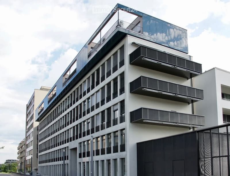 Modern multi-story building with large windows, balconies, and a sleek design.