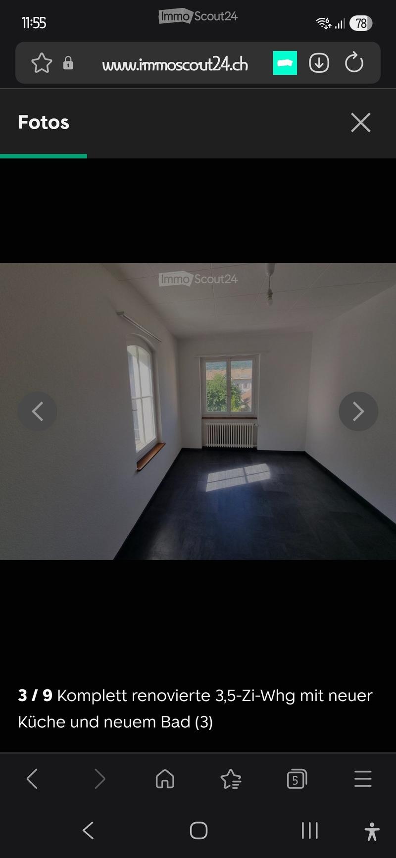 Empty room with bare walls, dark flooring, two windows, radiator, and a small wooden shelf on one wall.