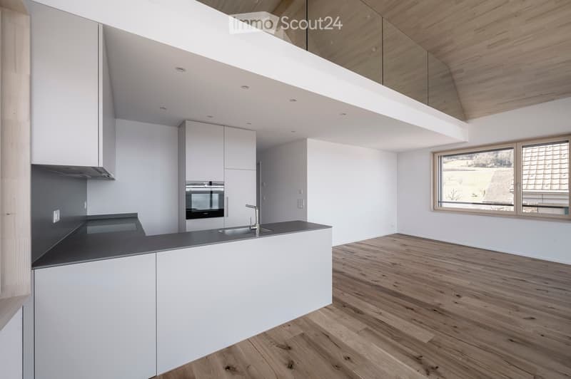 Modern kitchen with white cabinets, dark countertop, and wooden flooring. Features a sink, faucet, and built-in oven.