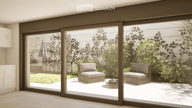 Modern balcony with large glass sliding doors, two beige chairs, a small table, and lush greenery visible outside.
