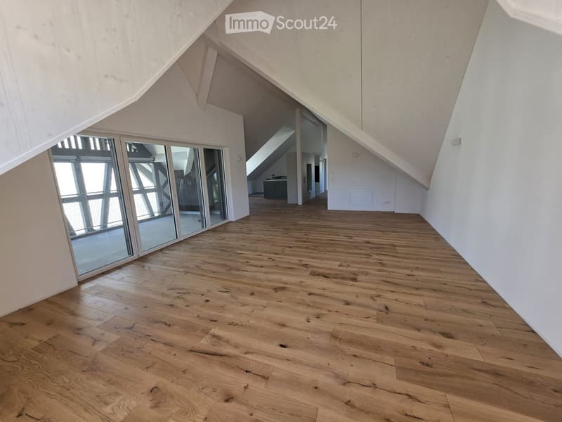 Empty room with wooden flooring, white walls, and large glass sliding doors leading to another space.
