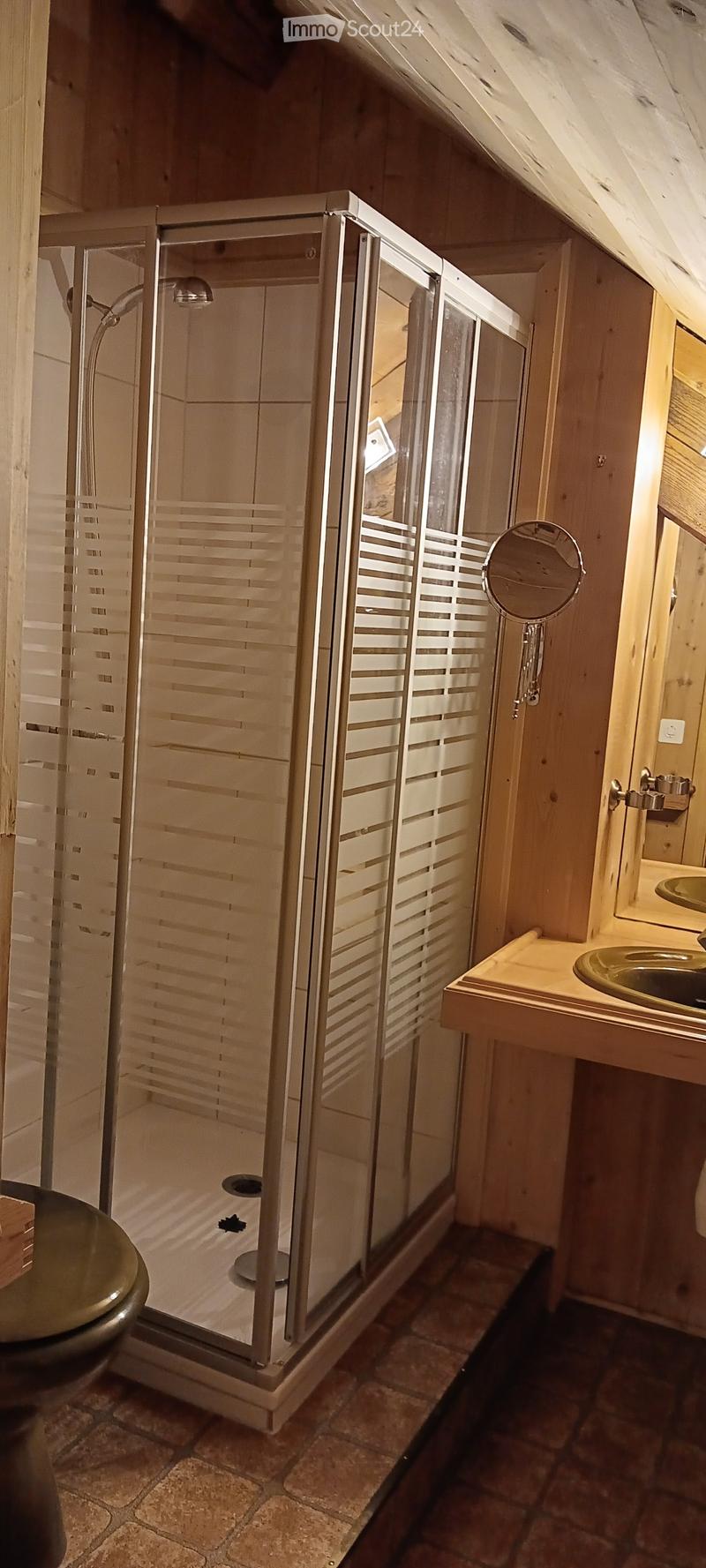 Modern bathroom with a glass-enclosed shower, wooden walls, and a sink with a mirror.