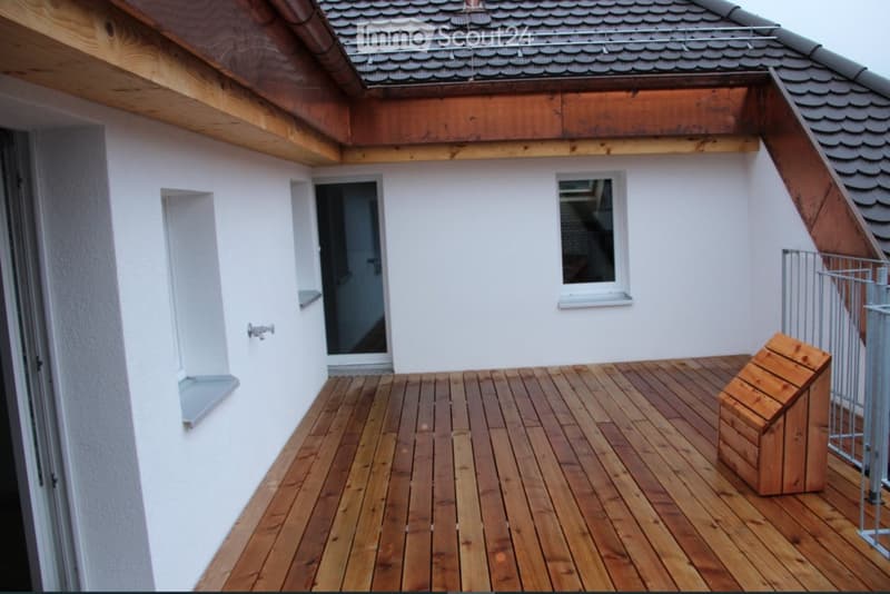 Wooden deck with white walls, small window, and a wooden storage box.