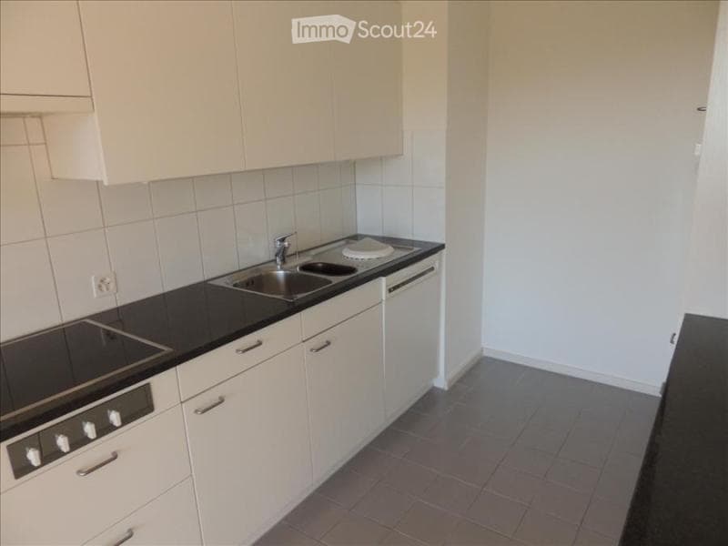 Modern kitchen with white cabinets, black countertops, stainless steel sink, and built-in oven.