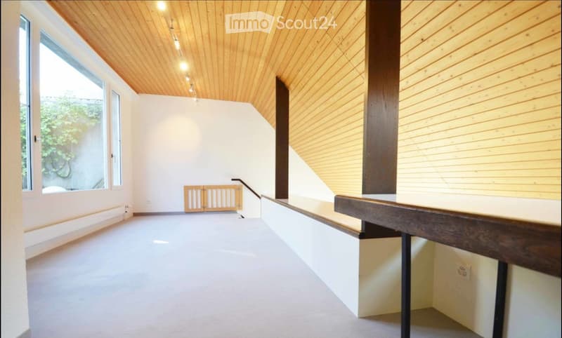 Modern, minimalist hallway with wooden ceiling, white walls, large windows, and a staircase leading upwards.