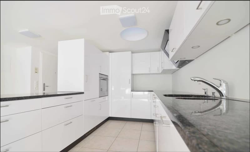 Modern kitchen with white cabinets, dark countertops, and stainless steel sink and faucet.